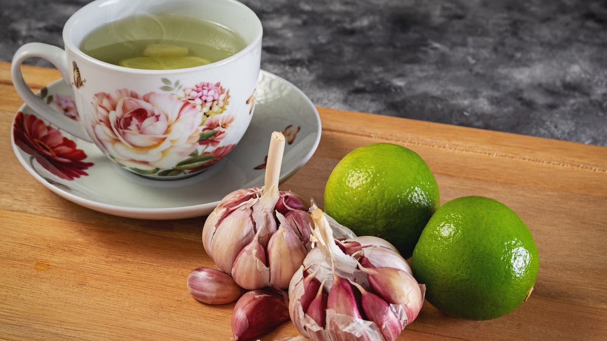 Close-up of herbal tea with garlic and limes on a wooden cutting board, perfect for food photography.